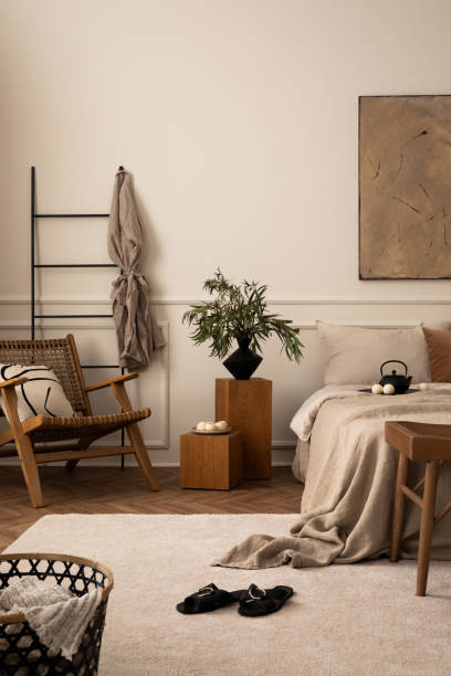 istock Creative composition of bedroom interior with mock up poster frame, cozy bed, beige bedding, wooden bedside table, rattan armchair, patterned pillow and personal accessories. Home decor. template. 1716608947
