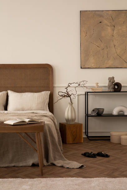 istock Creative composition of bedroom interior with mock up poster frame, cozy bed, beige bedding, black rack, wooden bench, bright rug, vase with branch and personal accessories. Home decor. Template. 1716608967