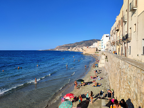 People refreshing at a public beach by the mura di Tramontana in the historic old town of Trapani, a city and municipality on the west coast of Sicily, in Italy.