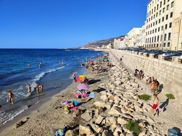 People refreshing at a public beach by the mura di Tramontana in the historic old town of Trapani, a city and municipality on the west coast of Sicily, in Italy.
