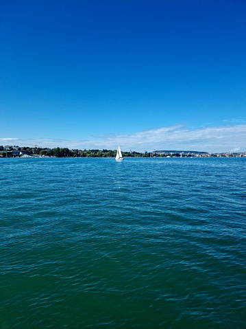The image was captured from a sailboat on lake Zurich. The beautiful Lake with some sailboats in autumn season.