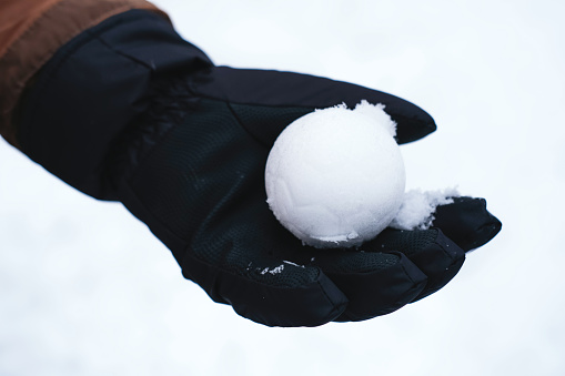Close-up of a snow ball in a gloved hand.