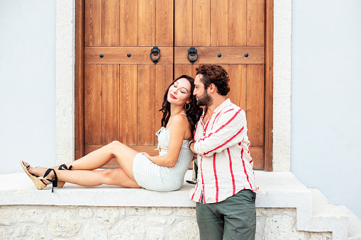 Portrait of a loving couple standing in front of a wooden door. Caucasian beautiful brunette with boyfriend very happy, outdoors