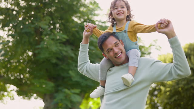 Smile, piggyback and father with girl in nature, bonding and having fun. Happy, dad and carrying child on shoulders, play and enjoying quality family time together outdoor in park with love and care.