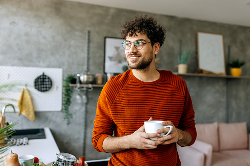 Young man enjoying a cup of coffee in his domestic kitchen