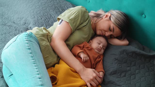 Young mother with diabetes and baby napping at home