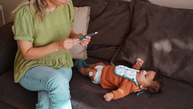 Mother checking the blood sugar of her baby with diabetes