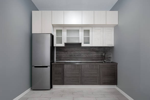 istock Modern kitchen interior with refrigerator, sink, chrome kitchen faucet and black hob. Light top and dark bottom of facades. The whole front view. 1716653791