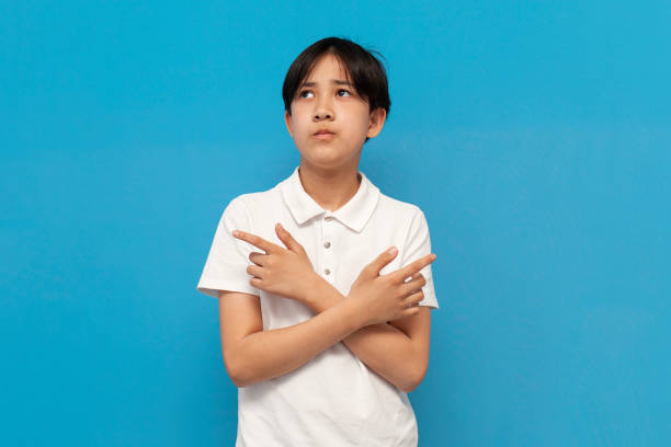 istock asian boy of twelve years old chooses between two options on blue isolated background, unsure korean child 1716656604