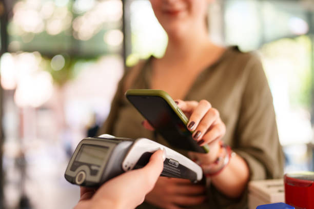 istock Young woman paying with mobile phone at the cafe. 1716679625