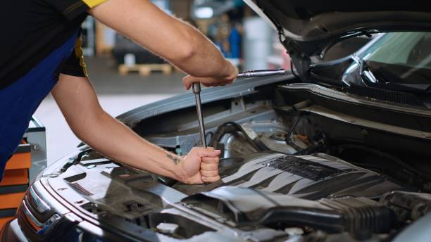 istock Employee in car service uses wrench 1716699403
