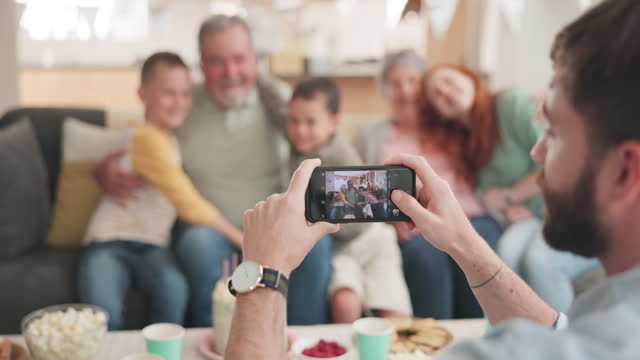 Phone, screen and photographer for family together in home with grandparents, children and mom in a picture or memory. Group, mobile and focus on lens, app or capture portrait of people on smartphone