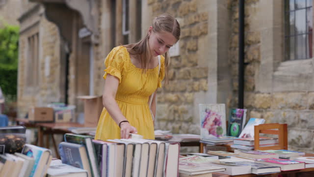 Teenage girl browsing book in a charity street market.
