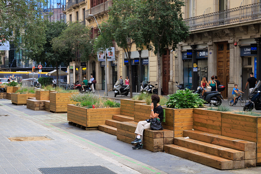 Barcelona, Spain - September 17, 2023: Benches and planters in the street in Barcelona, Spain. These pieces of street furniture take the place of former parking spaces, and provide people with a place to socialise and rest.