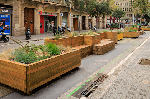Barcelona, Spain - September 17, 2023: Benches and planters in the street in Barcelona, Spain. These pieces of street furniture take the place of former parking spaces, and provide people with a place to socialise and rest.