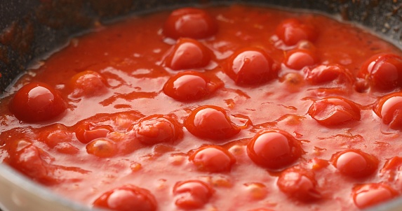 Tomatoes in their own juice are fried or boiled in a pan with bubbles and steam. Cooking bolognese sauce. Food preparation in the kitchen. A series of photos to visualize the recipe.