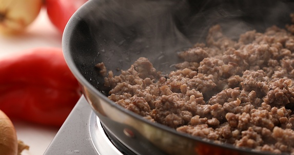 Minced meat is fried in a pan with steam. Cooking bolognese sauce. Food preparation in the kitchen. A series of photos to visualize the recipe.