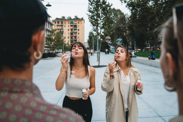 Friends playing with soap bubbles together in the city. They are having fun together.