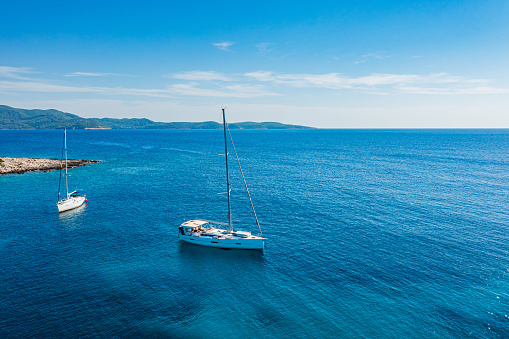 Anchored sailboat at Perna cove, Proizd island, Dalmatia, Croatia. High angle view from drone. Model released.