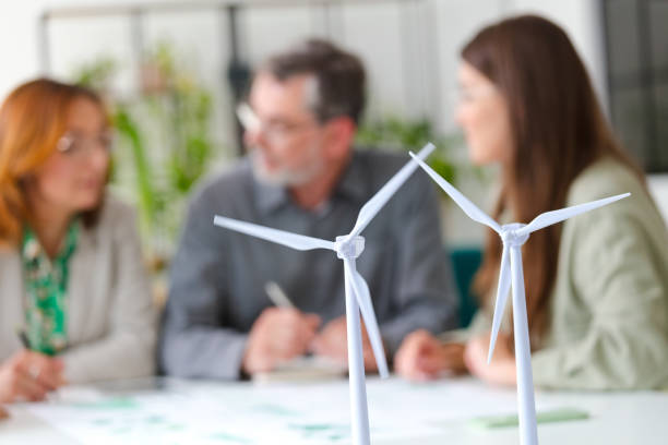 Wind turbine models against colleagues discussing in office