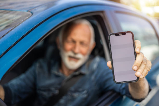 istock Smiling mature man showing smartphone with blank screen while sitting in new car. 1716799821