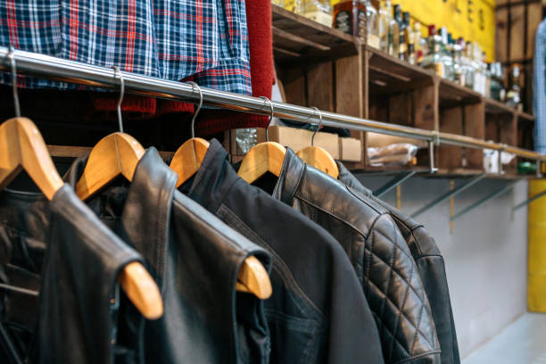 istock Second hand black leather vests and jackets in hangers on vintage clothes shop with copy space 1716807783