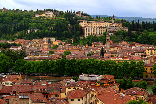 Photo with a panoramic view of part of the historic center of Verona with numerous churches and the walls of the castle on a green hill