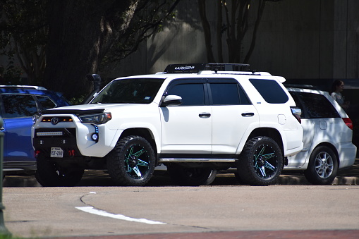 Houston, TX USA 10-1-2023 - A white Toyota Forerunner with custom blue wheels cruising near Herman Park in Houston
