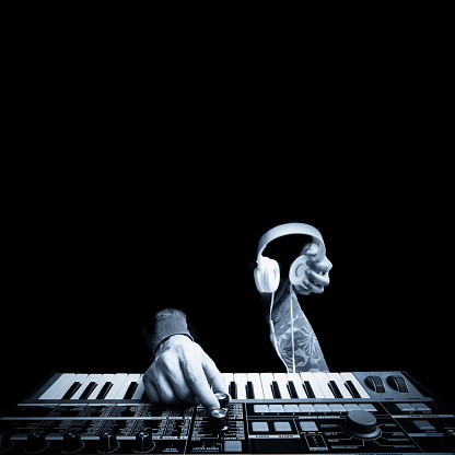 musician hands playing keyboard synthesizer and holding headphone. black and white. music concept