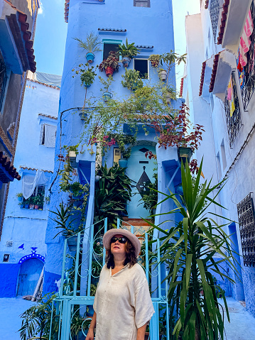 Woman walking in alley of Chefchaouen, Morocco. The colorful blue walls of the city make this a unique city.