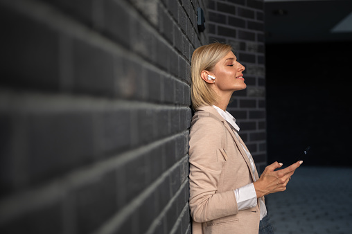 Business woman leaned on brick wall using phone