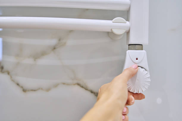 istock Electric wall-mounted heating radiator, hand on temperature thermostat 1716886813