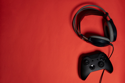 top view of a headset and a gaming control with red background and copy space