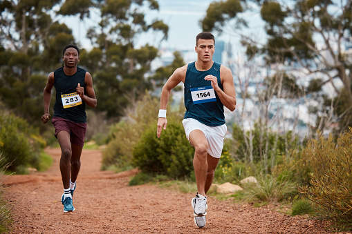 Marathon, race and people running in nature for fitness competition or sports challenge. Runner or athlete men together for exercise, workout or cardio performance with speed, commitment and wellness