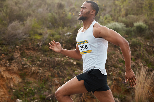 Marathon, exercise and black man running outdoor in competition, workout and training for healthy body or wellness. Fitness, sports and runner athlete in race, cardio and energy in the countryside
