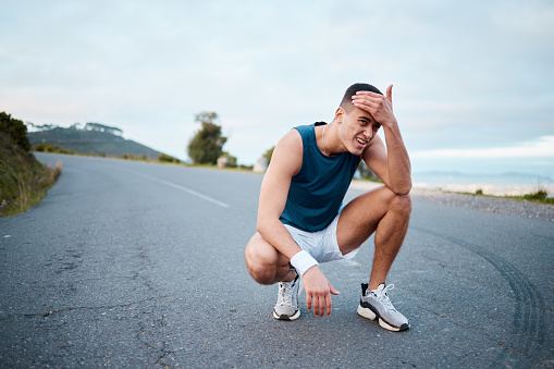 Fitness, tired or man on break in running training, cardio workout and exercise outdoors. Runner breathing, sports or athlete exhausted with fatigue resting to recover energy in marathon race on road