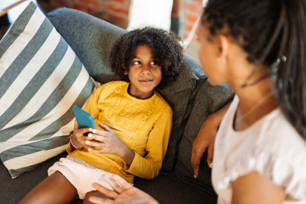 istock African American girl using cell phone while talking to her mother 1716921263