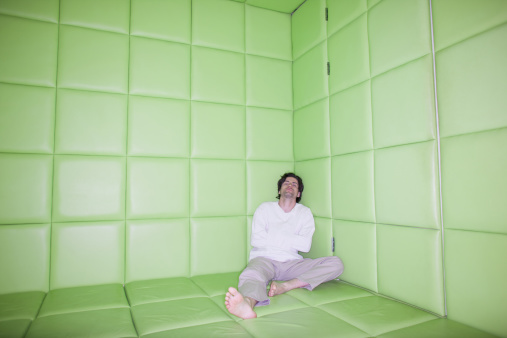 Man sitting with legs apart in padded room