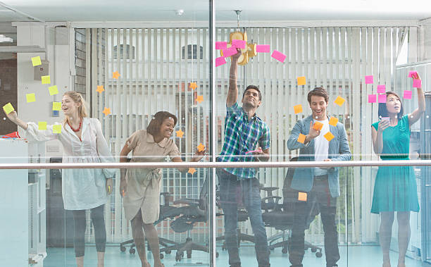 Excited business people with arms raised at window covered in adhesive notes  five people photos stock pictures, royalty-free photos & images