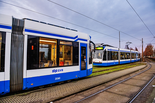 In Amsterdam, Netherlads GVB trams driving in opposite directions provide public transportation across the city.