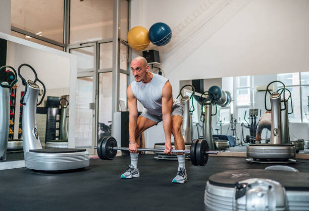 istock Man exercising with a barbell in a gym 1716941904