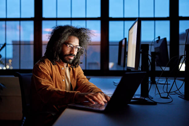 Bearded office worker using laptop and desktop pc