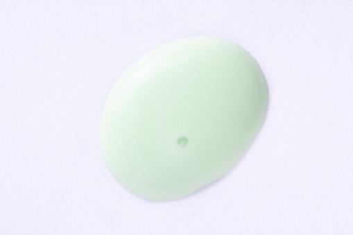 Cosmetic light green cream blob swatch on white background. Pastel green face cream, makeup primer, color correcting cosmetic product, serum