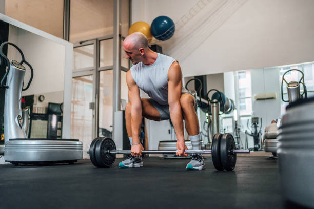 istock Man exercising with a barbell in a gym 1716965508