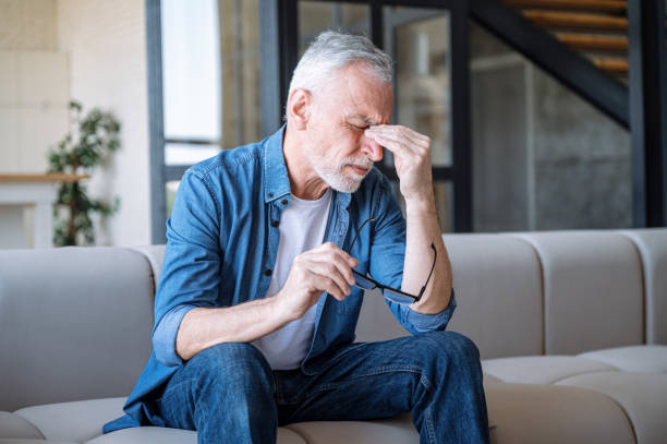 Man holding glasses and touching nose bridge, feeling eye strain