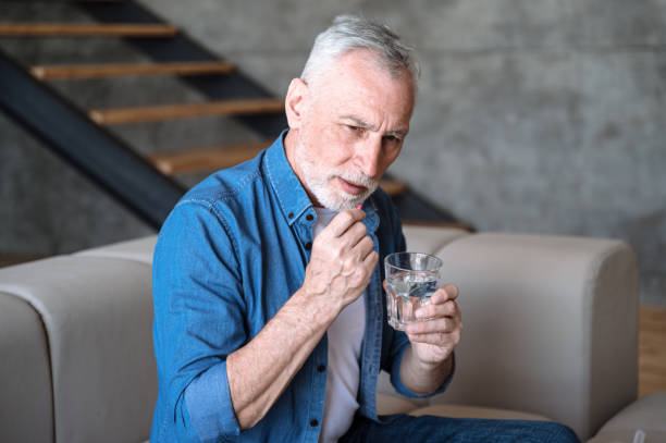 istock Mature man feeling sick and taking antibiotic pill at home 1716970576
