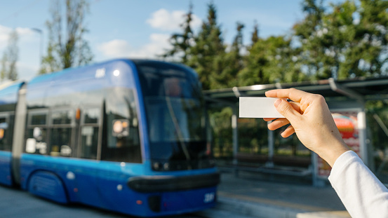 Selective focus on one-way train ticket in tourist hand for travel against blurred platform background. Comfortable trip i modern transport. Copy space.