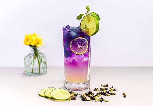 Lemonade with butterfly pea flowers and blue syrup on light gray background with copy space