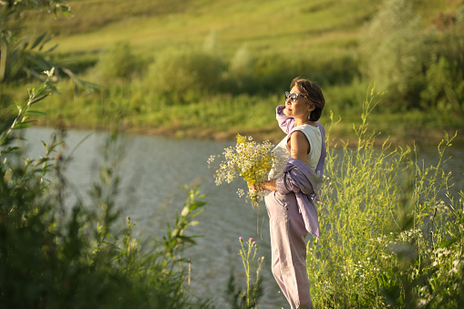Senior woman with wildflowers, an embodiment of the relaxation and tranquility that wellness retreats can provide.