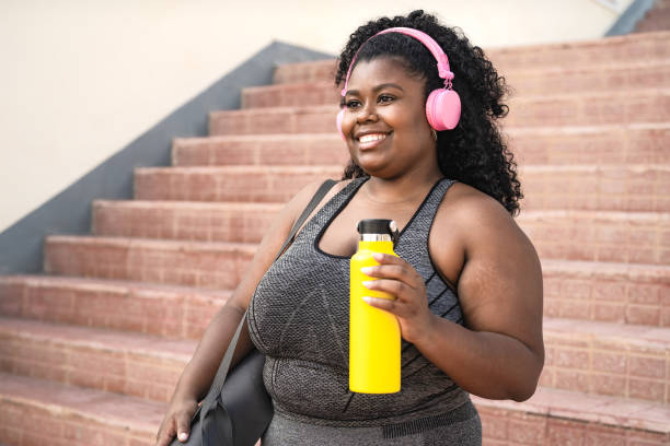 istock Happy plus size African woman doing workout routine while listening music with wireless headphones outdoor 1716978025